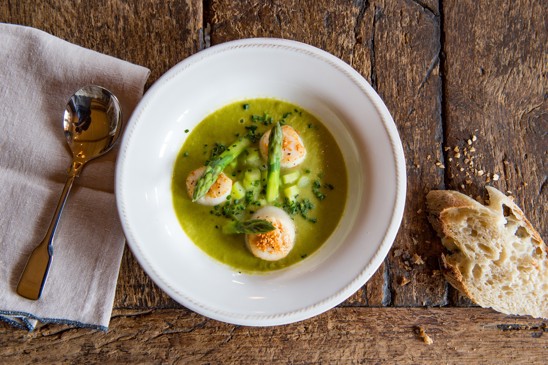 A bowl with cooked fish and asparagus with a side of fresh bread.